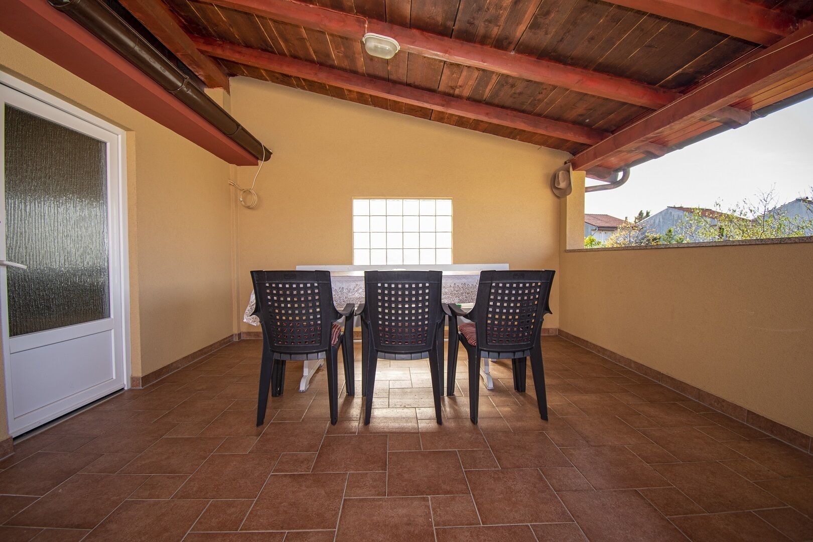 An outdoor patio with a table and chairs, a sliding glass door, and a view of the neighborhood.
