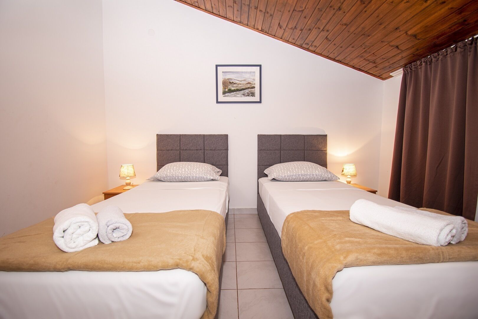 A twin room with two beds, each with a headboard, bedside lamps, and towels.