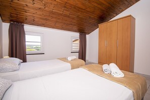 Ein Hotelzimmer mit zwei Betten, Holzboden und einem Kleiderschrank.