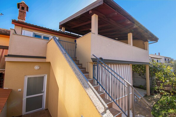 Ein zweistöckiges Haus mit einer Treppe, die zu einer überdachten Terrasse führt.