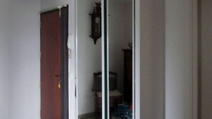 A room with a sliding glass door leading to another room, a wooden door, a ceiling light fixture, and a clock on the wall. - "Les Rousserolles"- Between LAC du BOURGET and CHAMBERY, T 2 (64m2), 3 stars NN (La Motte-Servolex)
