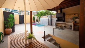 Ein Außenbereich mit Pool, Holzterrasse und Steinmauer.