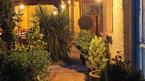 Un cortile con tetto in tegole, piante in vaso e una pergola in legno.