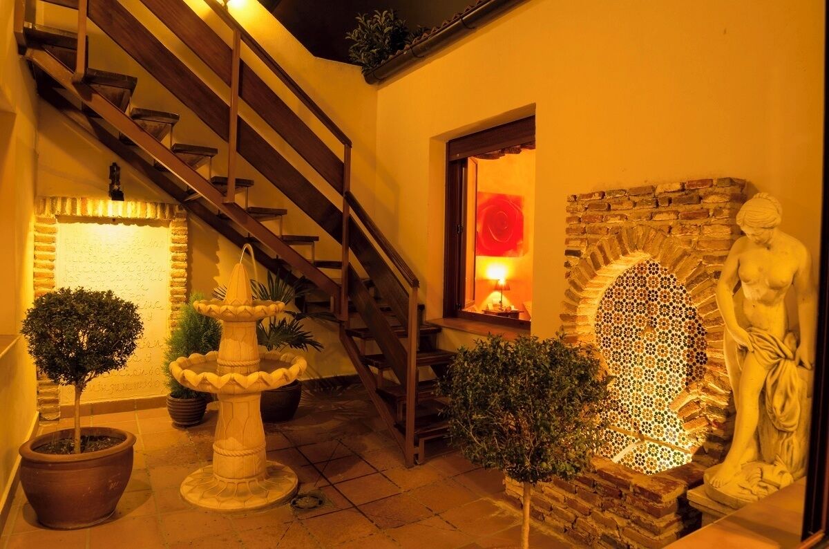 Una escalera que lleva a un nivel superior, una pared de piedra con un mosaico y una estatua.