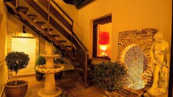 Una escalera que lleva a un nivel superior, una pared de piedra con un mosaico y una estatua.