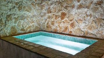 Un hidromasaje con paredes de piedra y un interior con azulejos.