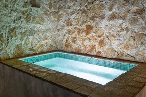 A stone-walled hot tub with a tiled interior.