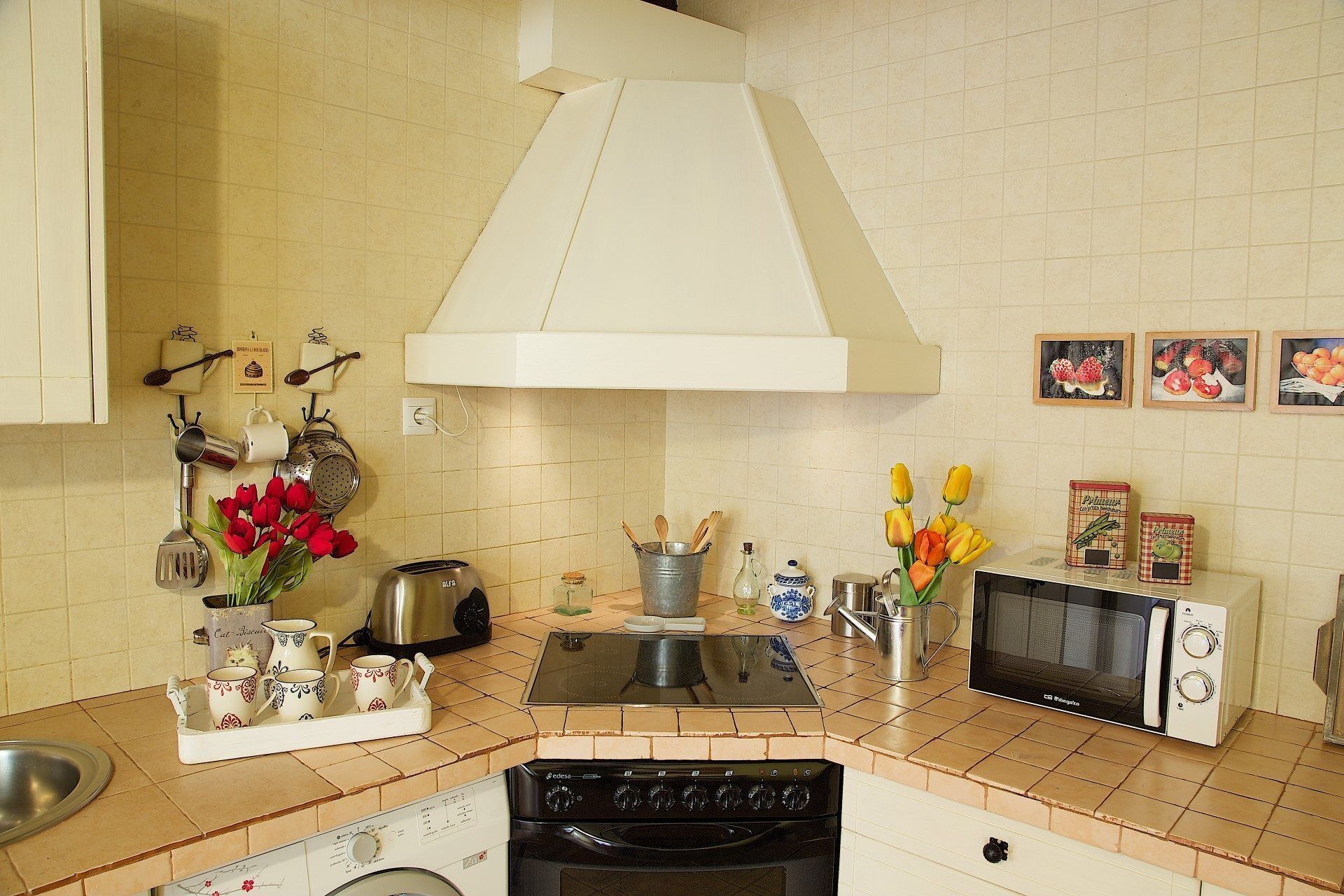 Una cocina con estufa, microondas y diferentes utensilios de cocina.