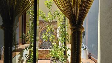 A courtyard with potted plants, a brick wall, and a window with a decorative screen.