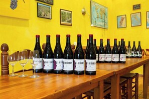 Une longue table en bois, sur laquelle sont disposées de nombreuses bouteilles de vin et des verres à vin vides.
