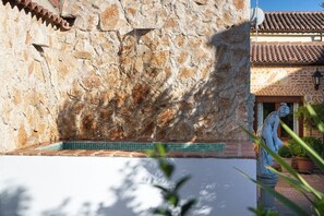 A stone wall with a tiled pool area and a statue.