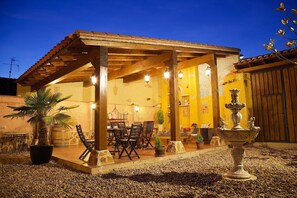 A covered outdoor seating area with tables and chairs, a fountain, and a rustic building with a tiled roof. - Self catering BEAUTIFUL ALAMEDAS***** for 13 people (Castronuño)