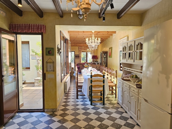 A kitchen with a checkered floor, wooden cabinets, a chandelier, and a dining area with a table set for four.