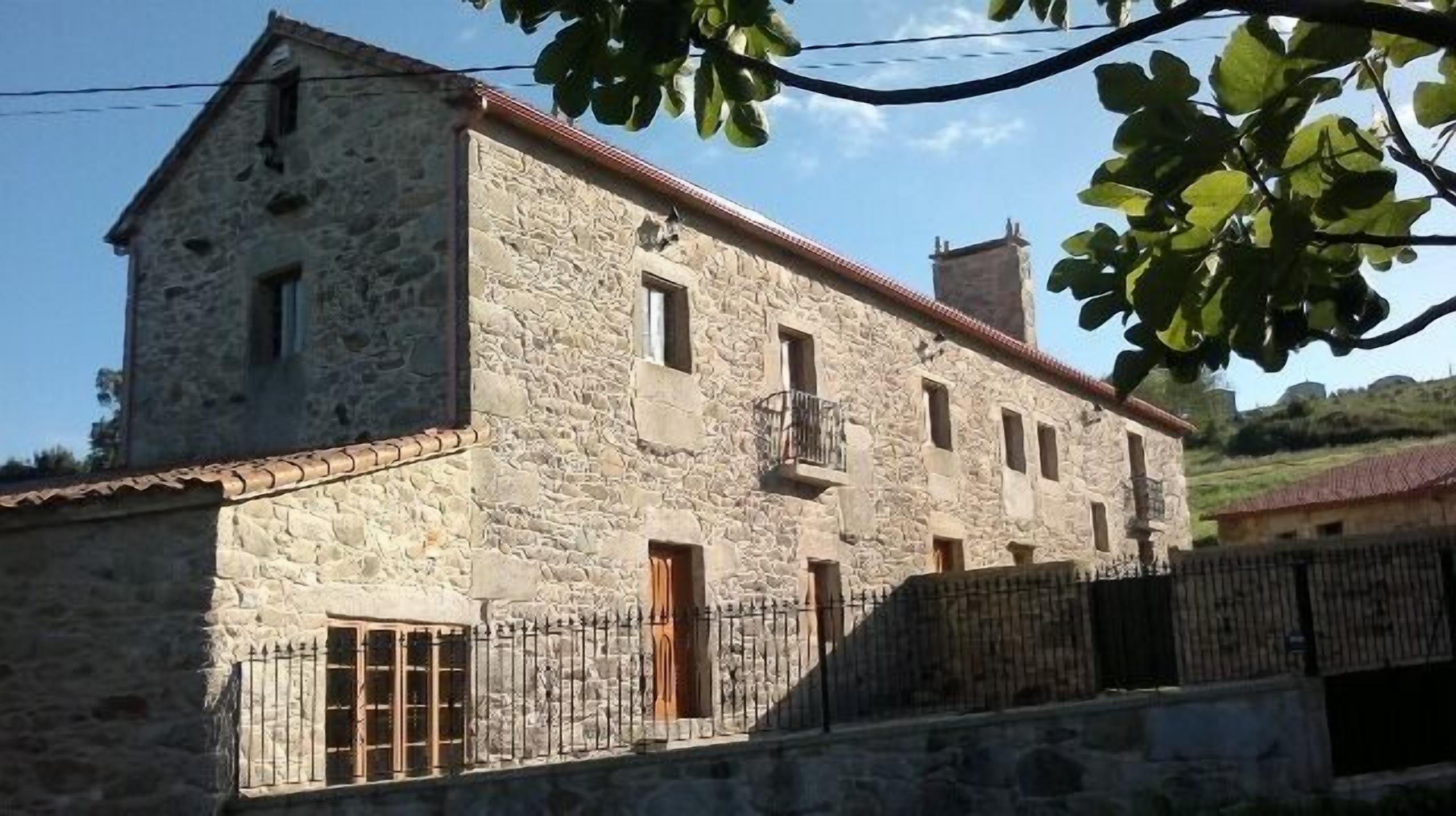 A stone building with a balcony, a wooden door, and a metal gate.