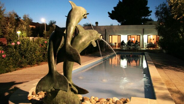 A sculpture of dolphins by a pool with a house in the background. - Three-room apartment in Residence - App 2 - with swimming pool near Vieste, Gargano, Puglia (Vieste)