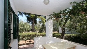 A covered patio with a table and chairs, surrounded by greenery and trees. - Three-room apartment in Residence - App 2 - with swimming pool near Vieste, Gargano, Puglia (Vieste)