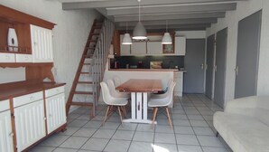Un espace de vie compact comprenant un coin repas, une kitchenette et un escalier menant à un niveau supérieur.