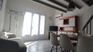 Un salon comprenant un coin repas, un téléviseur et un escalier.