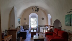 A spacious living room with a high arched ceiling, a fireplace, a red sofa, a wooden coffee table, and a brick accent wall.