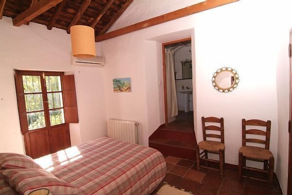 Une chambre  à coucher avec un lit, une fenêtre, un radiateur, un tableau et un miroir.