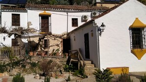 A traditional white building with a stone staircase, a wooden fence, and potted plants.