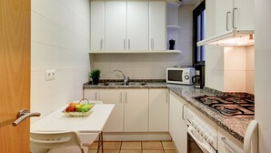 A compact kitchen with white cabinets, a microwave, a gas stove, and a small countertop. - P.C. LLEVANT 3 1 Roses (Rosas / Roses)