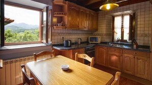 Eine Küche mit Holzausstattung, einem Esstisch und Blick ins Freie.