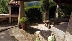 Ein überdachter Außenbereich mit Steinsitzen, einem Blumentopf und Blick auf die umliegende Landschaft.