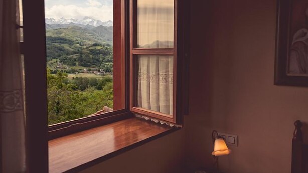 Ein Zimmer mit Fensterblick auf eine Berglandschaft.