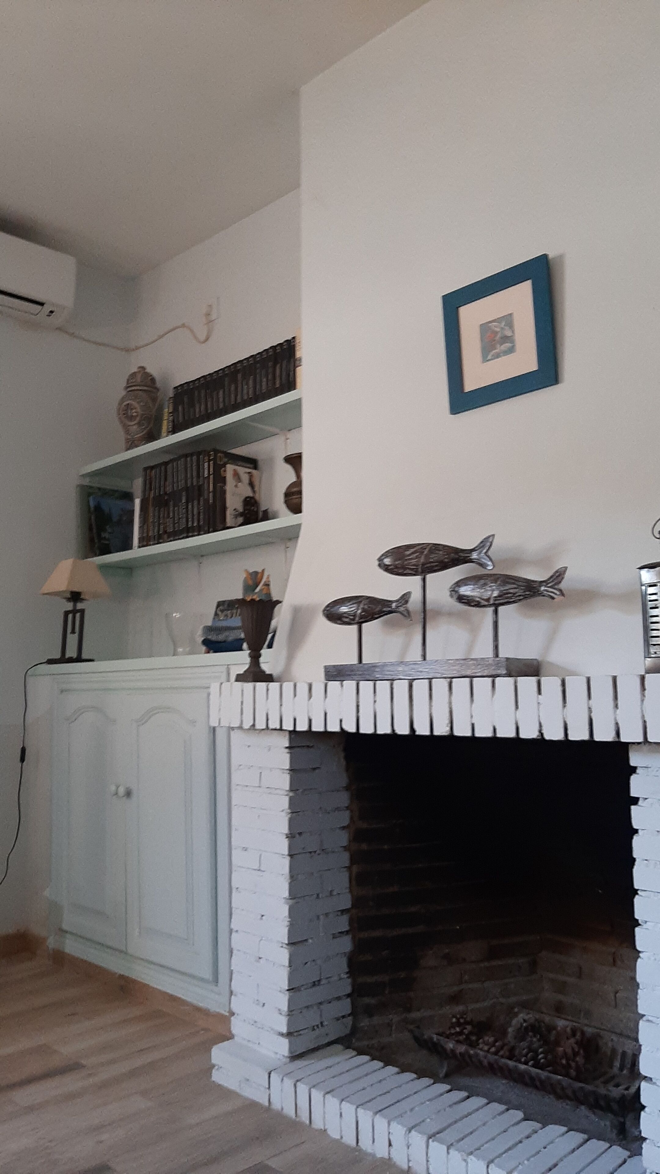A living room with a white fireplace, bookshelves, and decorative fish sculptures.