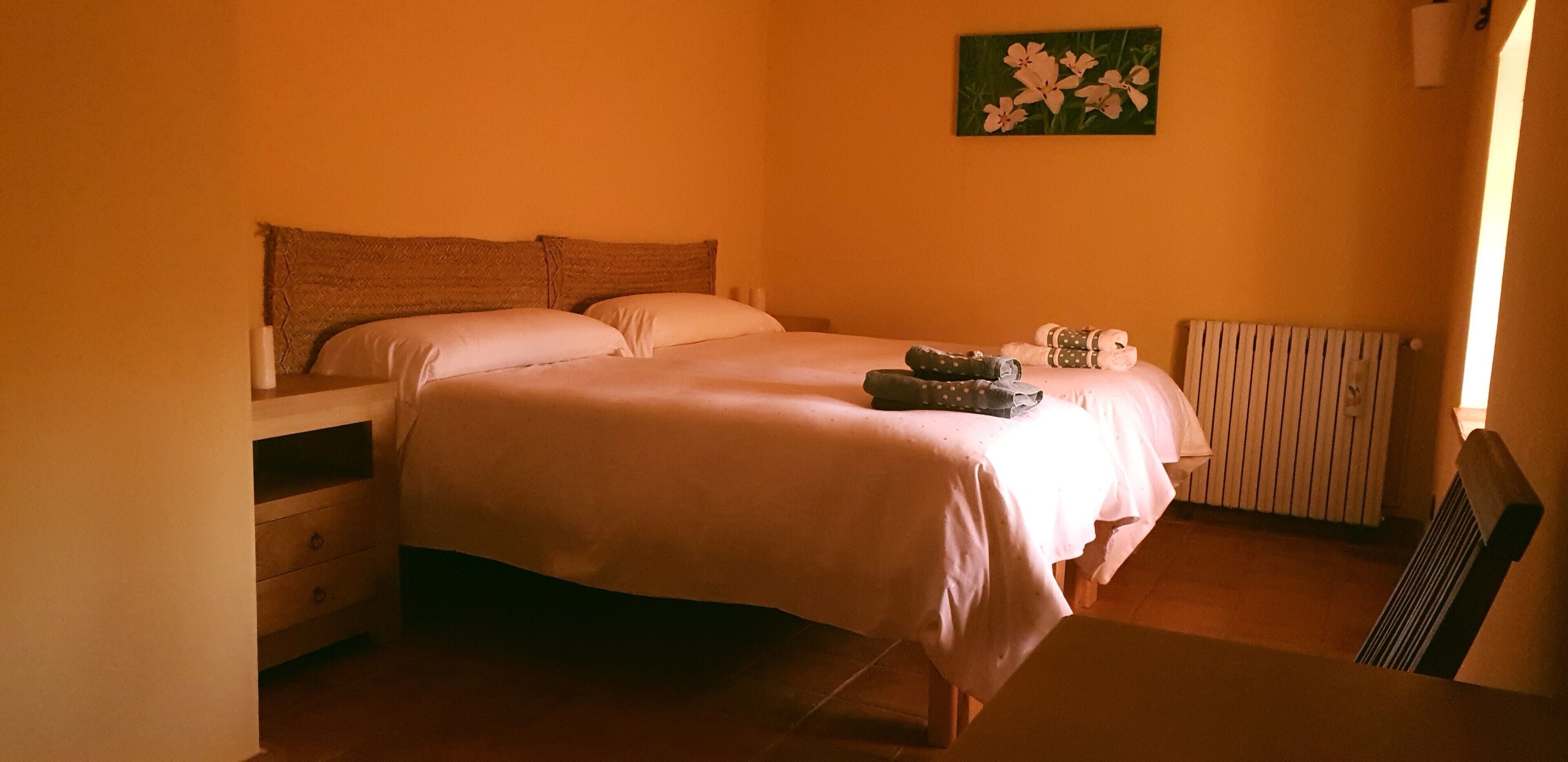 Un dormitorio con cama, mesita de noche, una silla y un radiador.