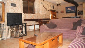 Una sala de estar acogedora con chimenea de piedra, una mesa de centro de madera, un sofá a rayas y un dardo en la pared.