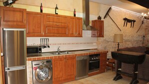 Una cocina con armarios de madera, electrodomésticos de acero inoxidable, lavadora y una parrilla.