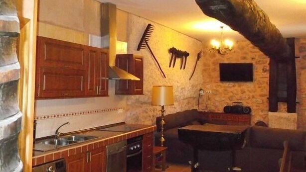 Una cocina rústica con armarios de madera, pared de piedra y un pilar de piedra.