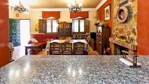 Un coin repas avec une table en granit, des chaises en bois et un mur rouge agrémenté d’une cheminée en pierre.