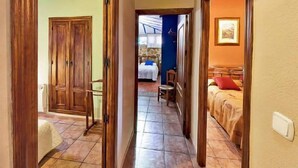 Un couloir mène à une chambre qui contient un lit, une chaise et une petite table.