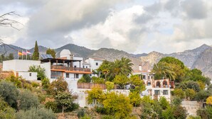 A hillside residential area with houses featuring balconies, solar panels, and a flag. - Alojamiento Rural El Valle for 6 people (Dúrcal)