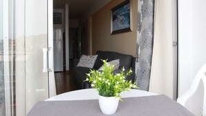 A room with a dining table, a potted plant, a sofa with cushions, and a painting on the wall. - Apartment right on the beach of Playa de La Arena, with balcony and sea view (Santiago del Teide)