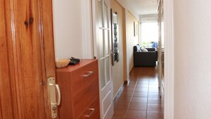 A hallway with a wooden door, a cabinet with drawers, and a refrigerator. - Apartment right on the beach of Playa de La Arena, with balcony and sea view (Santiago del Teide)
