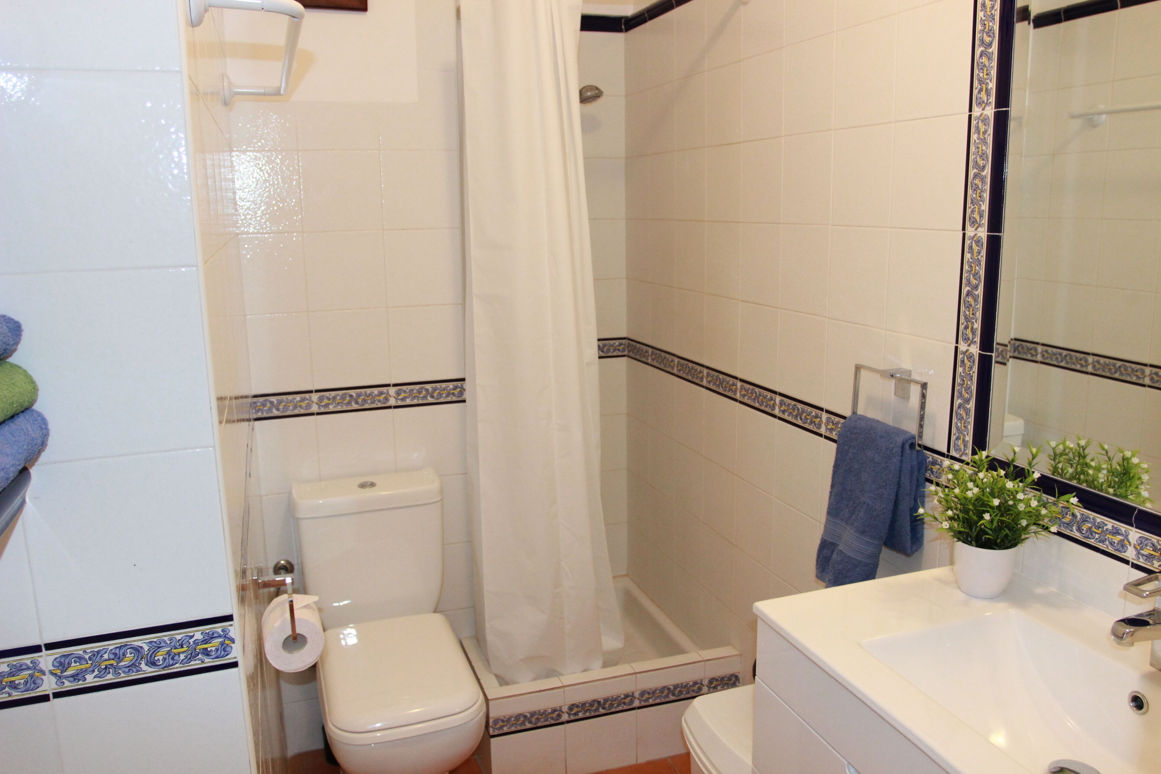 Een badkamer met toilet, douche, wastafel en een spiegel.