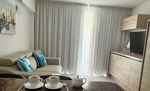 A modern living room with a sofa, a coffee table with cups and a teapot, a TV, and a cabinet. - Beautiful penthouse a few steps from the ocean (Costa Adeje)