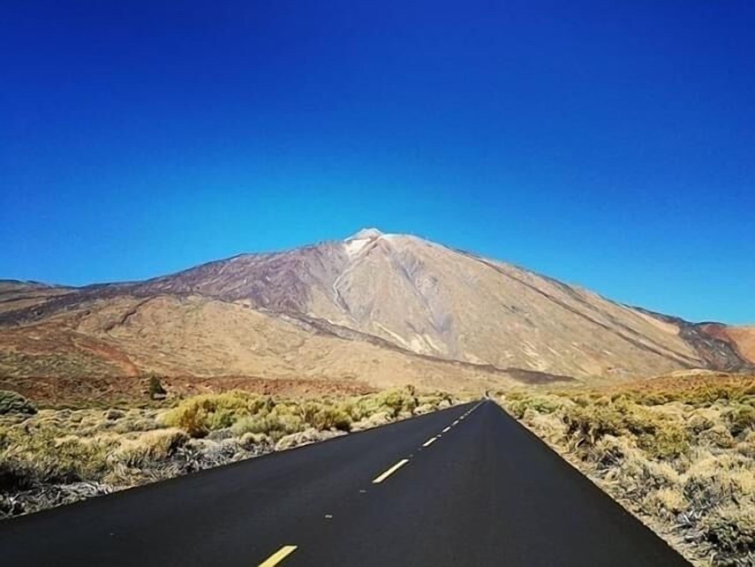 A road leading towards a mountain with a clear sky.