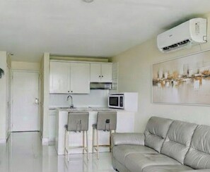 Una cocina moderna con armarios blancos, un microondas y un taburete de bar.