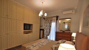 A bedroom with a bed, a dresser, a mirror, a TV, and a ceiling fan. - First floor independent apartment with amazing views & private pool in Pessada (Livathos)