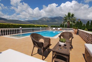 Un espace piscine aménagé sur le toit, avec des meubles en osier et une vue sur les montagnes.