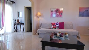 A living room with a sofa, a coffee table, a lamp, and artwork on the walls. - First floor independent apartment with amazing views & private pool in Pessada (Livathos)