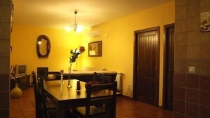 A dining area with a wooden table and chairs, a vase with flowers, and a painting on the wall. - Rural apartment Ramajal Rural for 4 people (Pinofranqueado)
