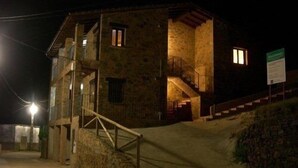 A stone building with a staircase leading to a second floor, a small balcony, and a sign on the right side. - Rural apartment Ramajal Rural for 4 people (Pinofranqueado)