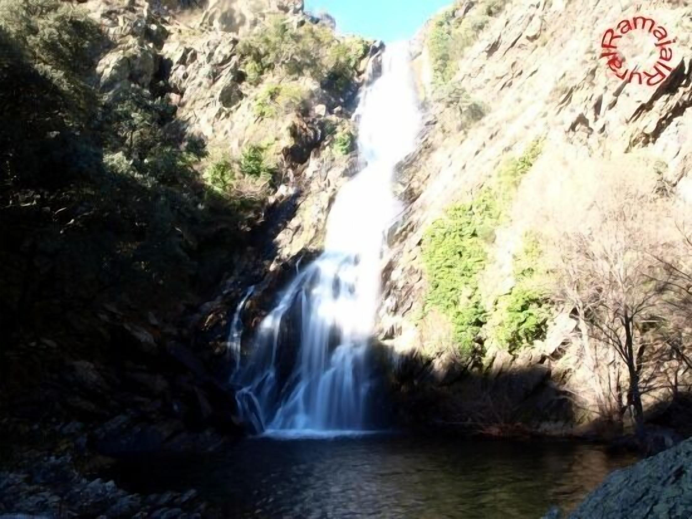 Une cascade se déversant en contrebas d’une falaise rocheuse dans un bassin.
