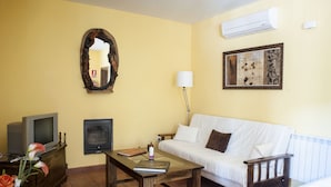 A living room with a sofa, a coffee table, a television, a fireplace, and a mirror on the wall. - Rural apartment Ramajal Rural for 4 people (Pinofranqueado)